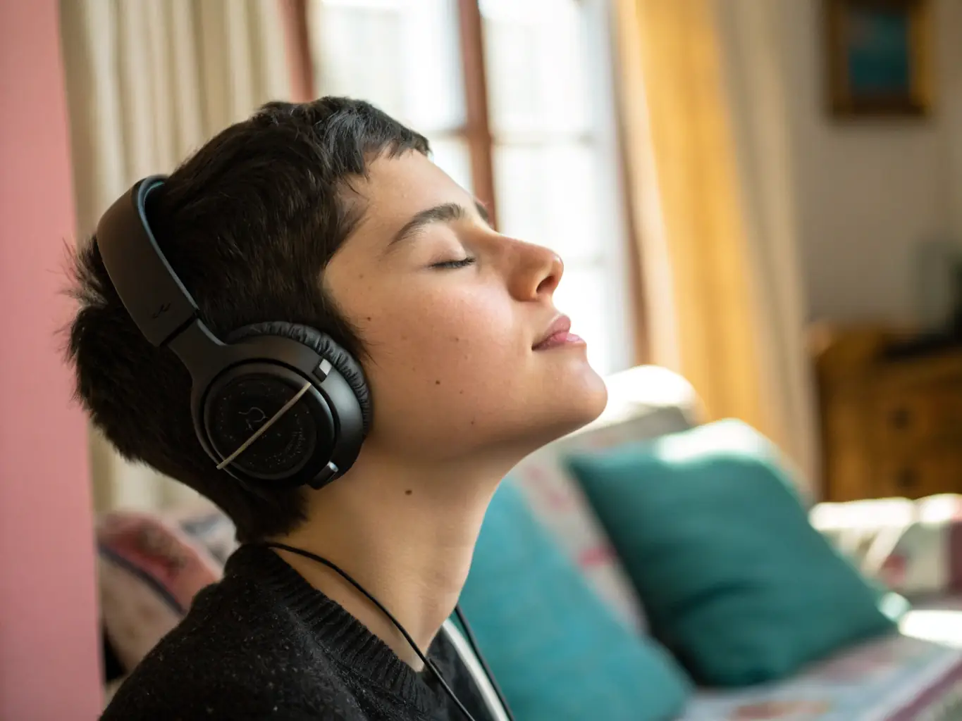 A person wearing noise-canceling headphones at an ASS MES MEUHS STRA concert, fully immersed in the music, with soft, ambient lighting.